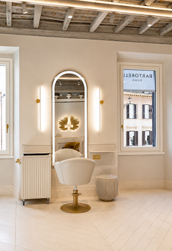 A single arched-mirror styling station beside a window looking onto Piazza di Spagna