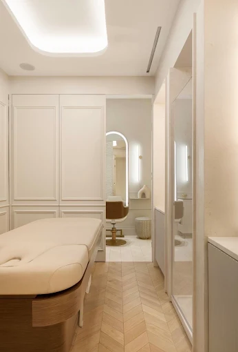 A private treatment room with a cream treatment bed and arched mirror